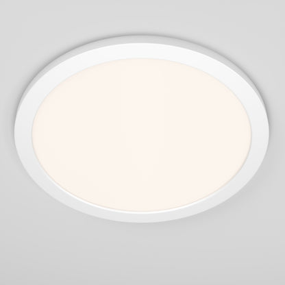 The Skylight Pro 15" 5K LED Flat Panel Light, an ultra-slim round white fixture with adjustable brightness, glows softly against a light gray ceiling.