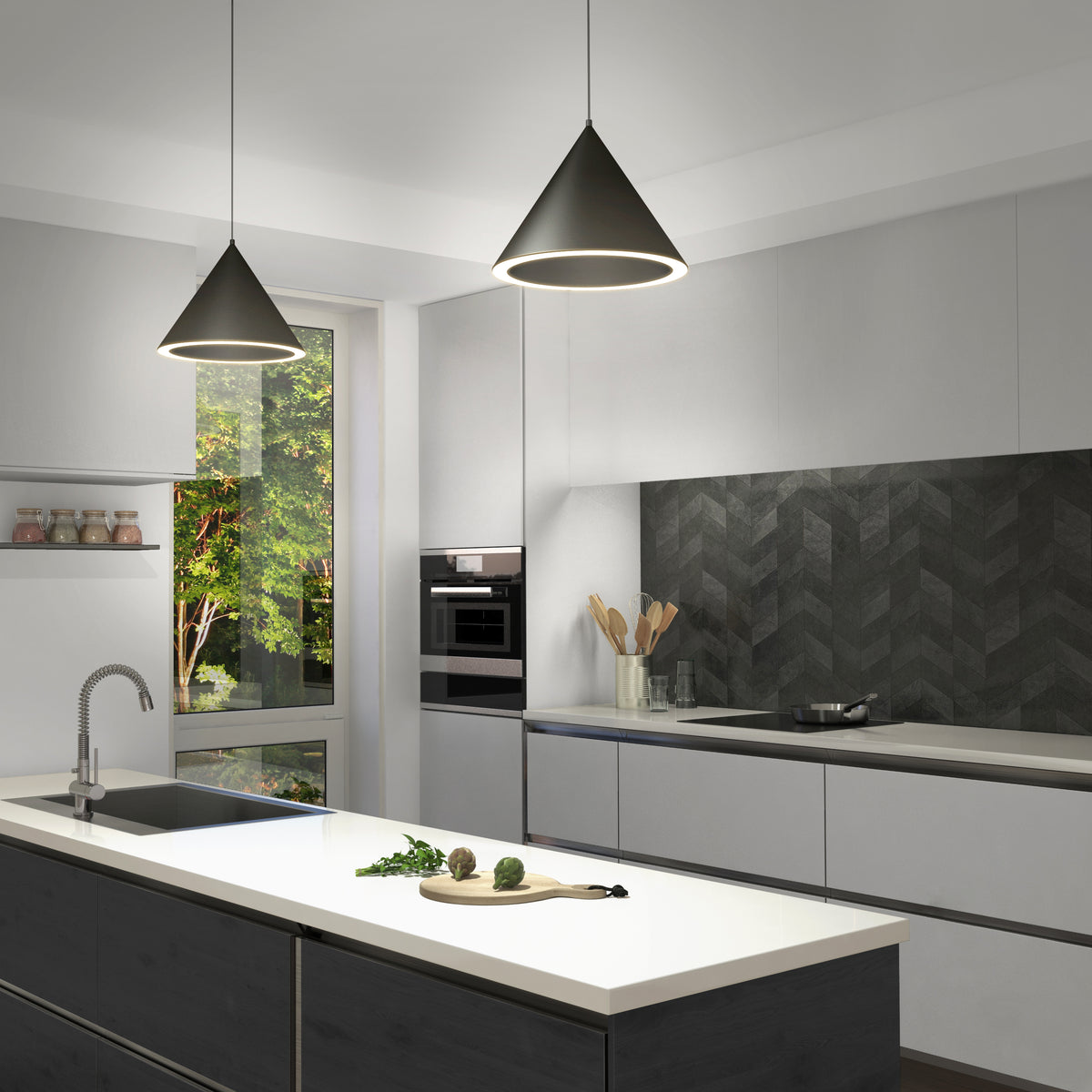 Modern kitchen featuring white cabinets, a dark herringbone backsplash, island with sink, and two Denali LED Pendant 3CCT lights. Large window brings in natural light with trees outside; utensils and jars add decorative touches.
