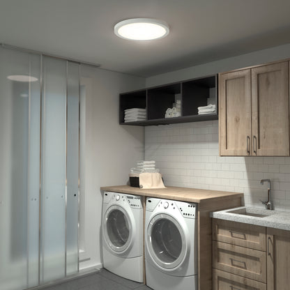 Modern laundry room with a wooden countertop over two front-load washers, open shelves of folded towels, light wood cabinets, tiled backsplash, and a Skylight Pro 15" 5K LED Flat Panel Light for adjustable brightness.
